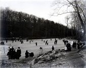 View of frozen lake on the Bronx River at Scarsdale with people engaged in ice skating and walking.